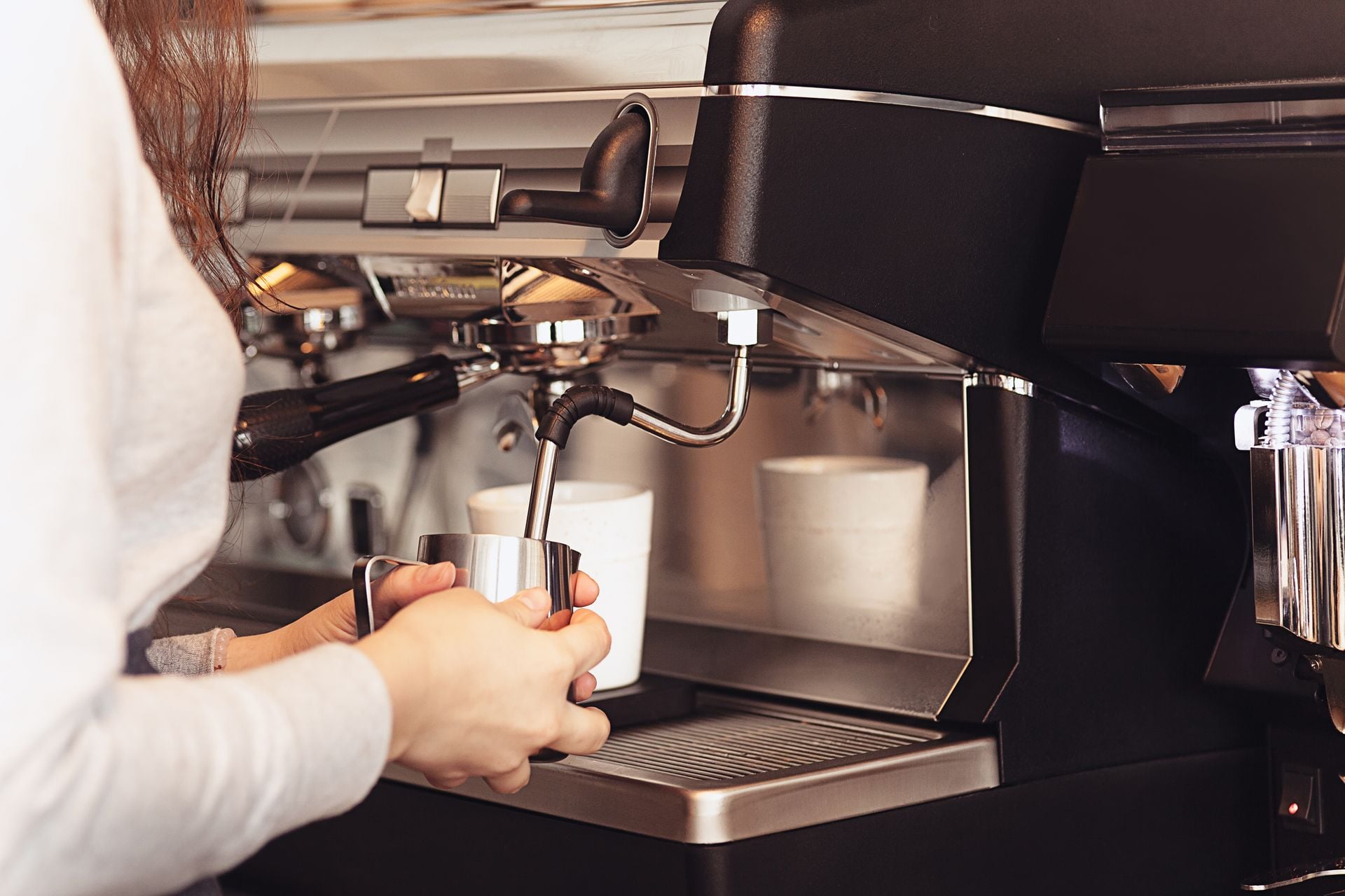 Barista steaming milk at a commercial espresso machine