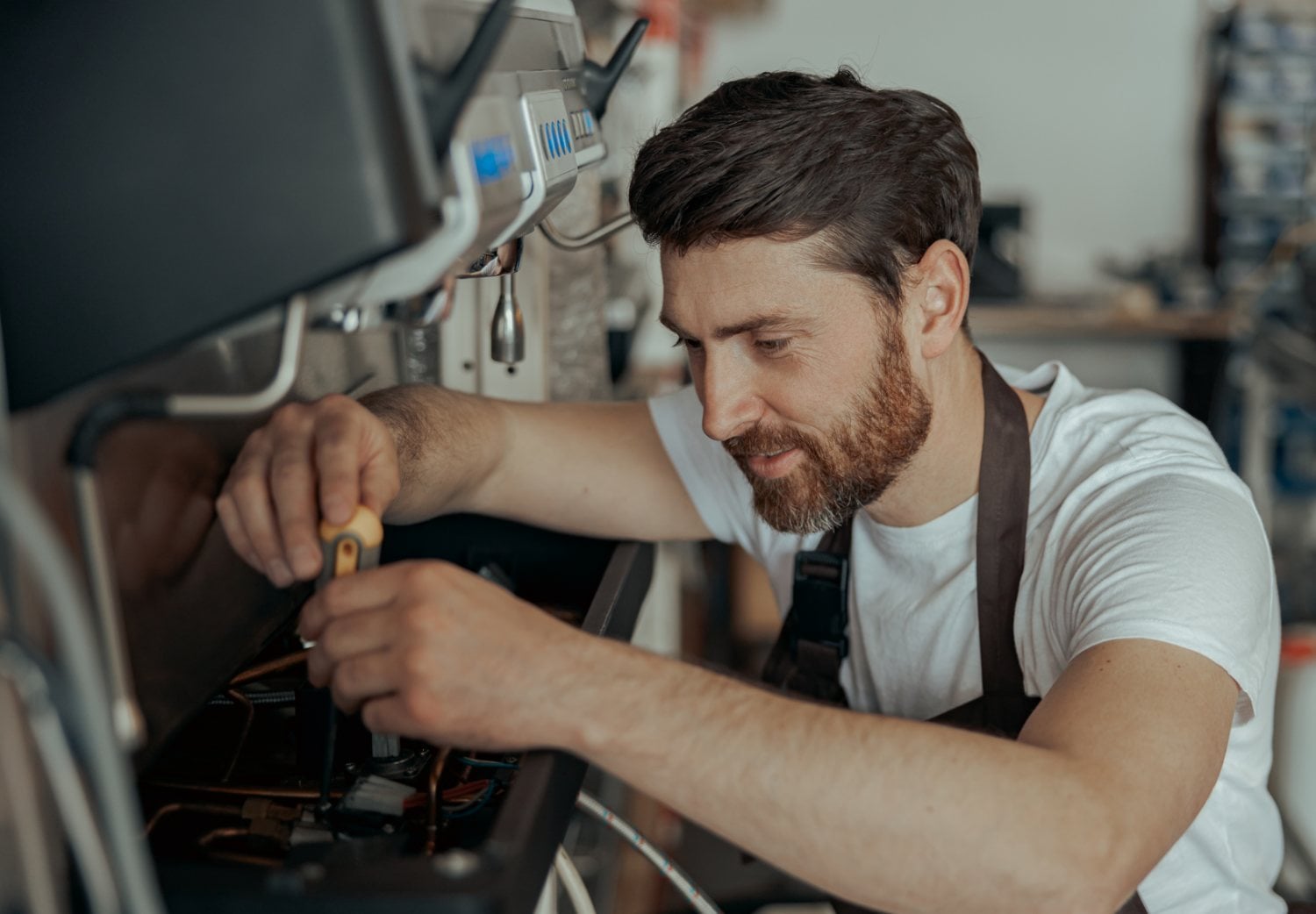 Smiling technician repairing a commercial coffee machine