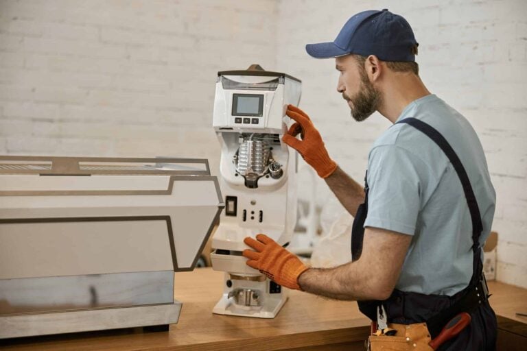 Technician repairing a commercial coffee machine in a UK cafÃ© in 2025